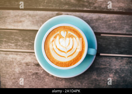Cappuccino mit aufgeschäumter Schaumstoff, blau Kaffeetasse obere Ansicht Nahaufnahme auf grau Holz- Hintergrund. Flach Stil. Stockfoto
