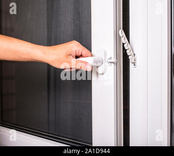 Mann öffnet sich PVC-Fenster mit Moskitonetz Sieb am Griff Stockfoto