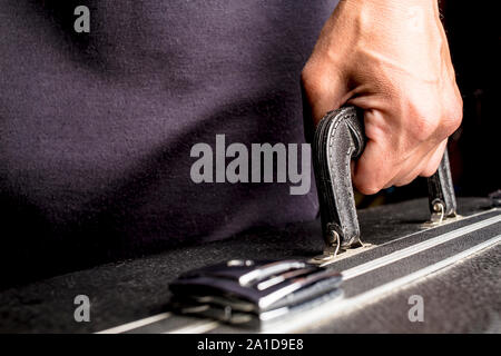 Der Mensch trägt einen schwarzen Koffer in der Hand auf dem Griff Stockfoto