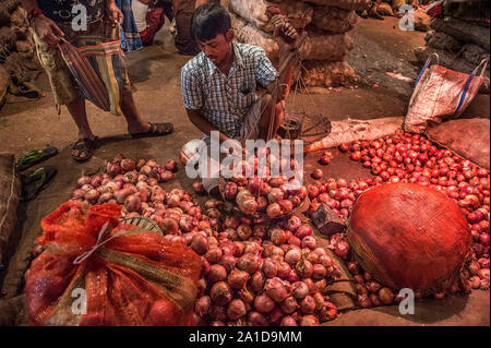 Kolkata, Indien. 25 Sep, 2019. Ein Verkäufer wiegt Zwiebeln für einen Kunden auf einer Zwiebel Großhandelsmarkt in Kolkata, Indien, Sept. 25, 2019. Preis der Zwiebeln haben stieg auf fast das Dreifache in den letzten paar Wochen in Indien, angeblich wegen der schweren Schäden zu erbringen bereit - für - Ernte Ernte im südwestlichen Bundesstaat Maharashtra und anderen nahe gelegenen Gebieten, durch die unaufhörlichen Regenfälle in diesem Jahr. Verkauft bei einem Preis von rund 20 indische Rupien ein Kilogramm in Delhi und anderen Teilen im Norden von Indien, die Ware wird jetzt bei fast 60 Indische Rupien ein Kilogramm erhältlich. Credit: tumpa Mondal/Xinhua/Alamy leben Nachrichten Stockfoto