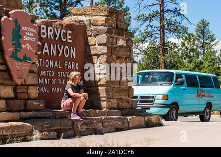 Bryce Canyon City, USA - August 1, 2019: Touristen fotografieren durch den Nationalpark Eingangsschild mit Frau für Foto- und Tour bus Posing Stockfoto