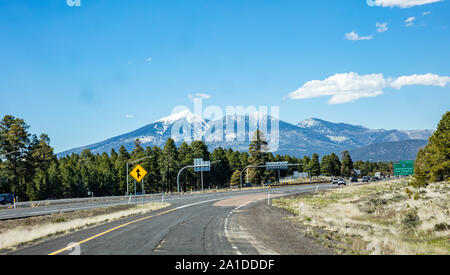 Arizona Highway, USA. Mai 26, 2019: Autobahn in der Nähe von Flagstaff, Schnee auf den Bergen, blauer Himmel, sonniger Frühlingstag Stockfoto