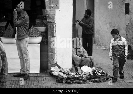 Ein Junge schaut auf Waren der Frau in Essaouira, Marokko, Afrika Stockfoto