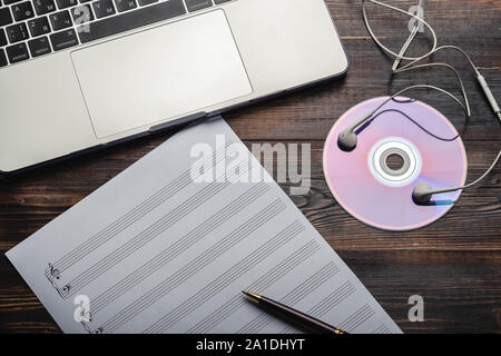 Laptop mit Kopfhörer, CD und Musik Papier mit Stift auf Holz- Hintergrund. Kopieren Sie Platz für Ihren Text. Ansicht von oben. Veraltete und moderne Storage Stockfoto