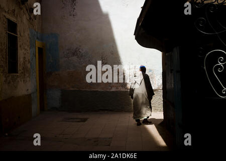 Ein Mann mit einem traditionellen Gewand dreht sich eine Ecke in Essaouira, Marokko, Afrika Stockfoto