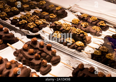 Früchte, Bananen, Erdbeeren, Nüsse, Äpfel, Pfirsiche in weißer und dunkler Schokolade getaucht. Stockfoto