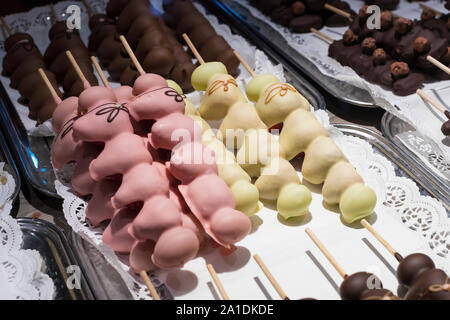 Früchte, Bananen, Erdbeeren, Nüsse, Äpfel, Pfirsiche in weißer und dunkler Schokolade getaucht. Stockfoto