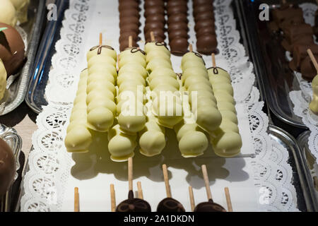 Früchte, Bananen, Erdbeeren, Nüsse, Äpfel, Pfirsiche in weißer und dunkler Schokolade getaucht. Stockfoto