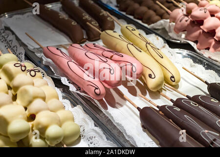 Früchte, Bananen, Erdbeeren, Nüsse, Äpfel, Pfirsiche in weißer und dunkler Schokolade getaucht. Stockfoto