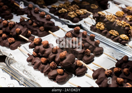Früchte, Bananen, Erdbeeren, Nüsse, Äpfel, Pfirsiche in weißer und dunkler Schokolade getaucht. Stockfoto