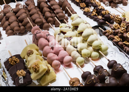 Früchte, Bananen, Erdbeeren, Nüsse, Äpfel, Pfirsiche in weißer und dunkler Schokolade getaucht. Stockfoto