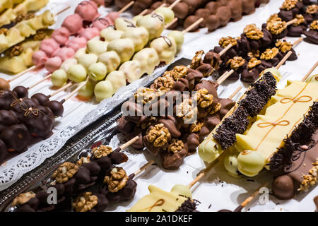 Früchte, Bananen, Erdbeeren, Nüsse, Äpfel, Pfirsiche in weißer und dunkler Schokolade getaucht. Stockfoto