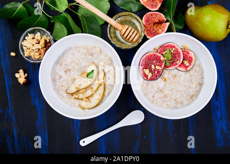 Eine Schüssel Haferbrei mit Birnen und Walnüssen und Haferbrei mit Feigen Stockfoto