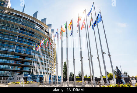Flaggen der Mitgliedstaaten der Europäischen Union mit Hintergrundbeleuchtung vor dem Eingang des Gebäudes des Europäischen Parlaments in Straßburg, Frankreich. Stockfoto