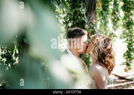Portrait von küssen paar im Garten. Blick durch baum laub Stockfoto