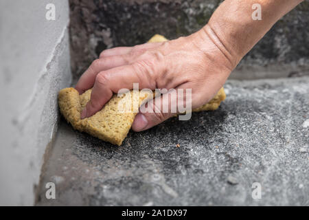 Der Mensch ist die Reinigung frische Mörtelfugen mit einem Schwamm Stockfoto