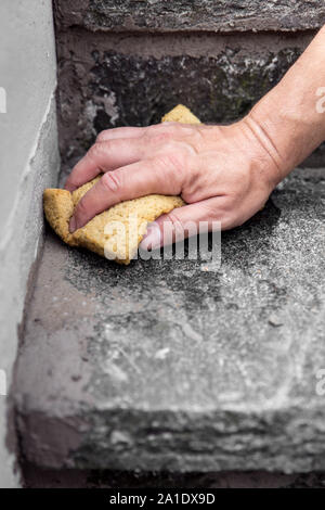 Der Mensch ist die Reinigung frische Mörtelfugen mit einem Schwamm Stockfoto