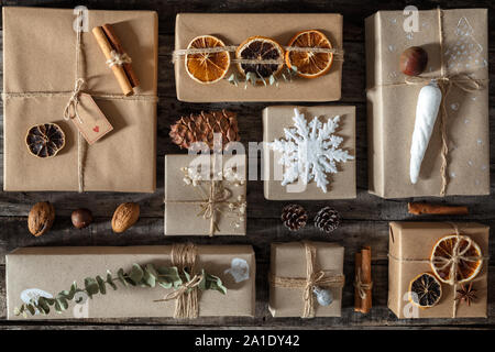 Kreativ verpackt und dekoriert Weihnachtsgeschenke in Kästen auf dunklem Hintergrund, flach. Stockfoto