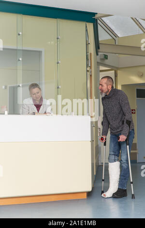 Patient wird im Gespräch mit einer Krankenschwester im Krankenhaus, stehend in einem Korridor Stockfoto