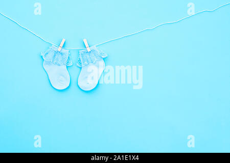 Paar blauen Cute Baby Socken hängen auf der Wäscheleine auf blauem Hintergrund. Baby Accessoires. Flach. Stockfoto