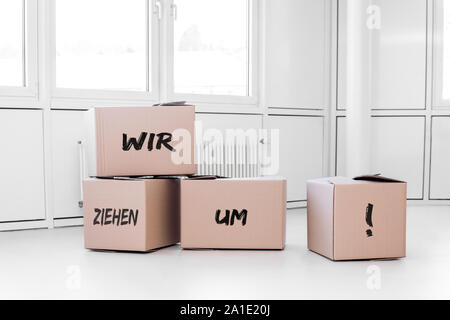 Weiße Zimmer mit Kartons und die deutschen Wörter wir ziehen um, was bedeutet, dass wir in Bewegung sind Stockfoto