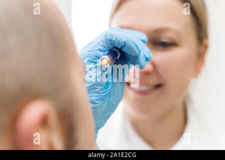 Weibliche professionell Specialist ist das Auge von einem männlichen Patienten mit einem elektrischen Licht prüfen Stockfoto