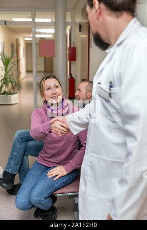 Arzt oder Chirurg gibt eine Frau ein Handshake im Flur oder Wartezimmer eine Klinik oder eine private Praxis Stockfoto