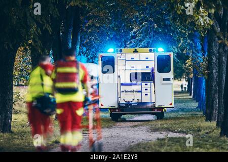 Sanitäter und Arzt drücken Bahre mit Patienten zu Rettungswagen. Themen Teamwork, Rettung und Hoffnung. Stockfoto