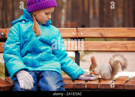 Mädchen füttern Eichhörnchen in der Sitzbank Stockfoto