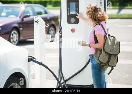 Eine Frau steuert eine Ladestation für Elektroautos Stockfoto