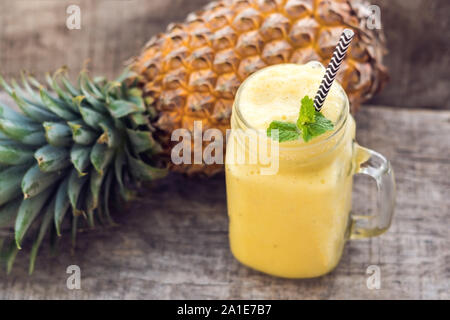 Ananas Smoothie mit frischer Ananas auf Holztisch. Stockfoto