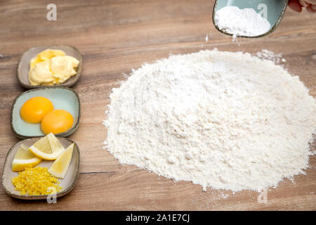 Backpulver oder Natron auf Holztisch, Eier, Butter und Zitrone auf der Seite Stockfoto