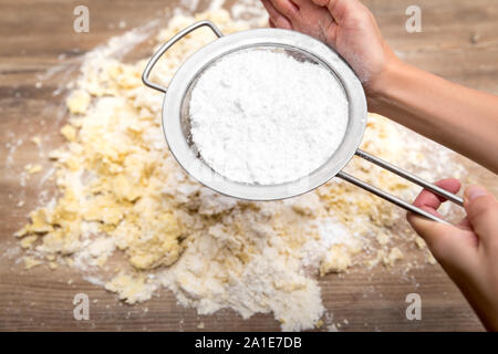 Frau sichten Puderzucker auf einer rohen Kuchen- oder Plätzchenteig, Bäckerei Schritt Stockfoto