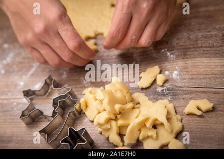 Frau ist Schneiden Plätzchenteig mit Weihnachten Thema Fräser, hölzernen Tisch Stockfoto