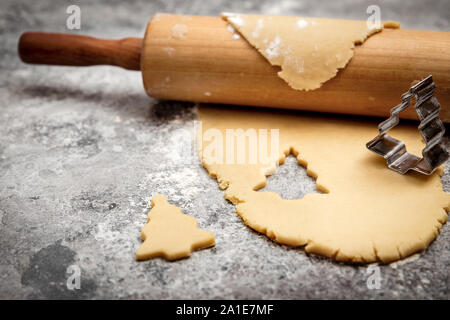 Plätzchenteig und Rolling Pin auf graue Tabelle, Weihnachtsbaum geformte Ausstecher Stockfoto