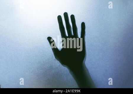 Der Schatten der menschlichen Hände hinter dem Glas. Stockfoto