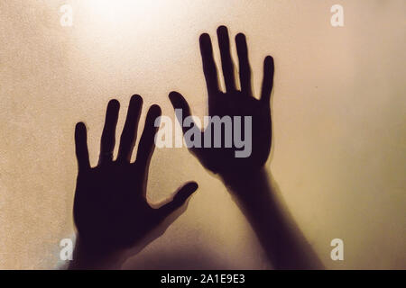 Der Schatten der menschlichen Hände hinter dem Glas. Stockfoto