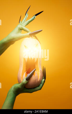 Bild von Green zombie Hand mit Kürbis auf leere orange Hintergrund Stockfoto