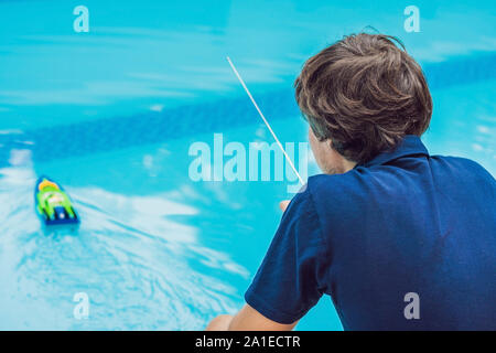 Mann spielt mit einem ferngesteuerten Boot im Pool. Stockfoto