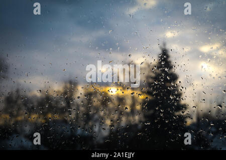 Textur von Wassertropfen auf Fensterglas und blurry Sunrise Landschaft. Stockfoto