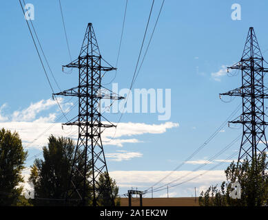 Zwei Masten der Hochspannungsleitung mit Glas Isolatoren und Leitungen vor einem blauen Himmel mit weißen Wolken Stockfoto