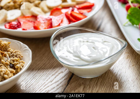 Joghurt in eine Glasschüssel mit gesunden Frühstück am Tisch Stockfoto