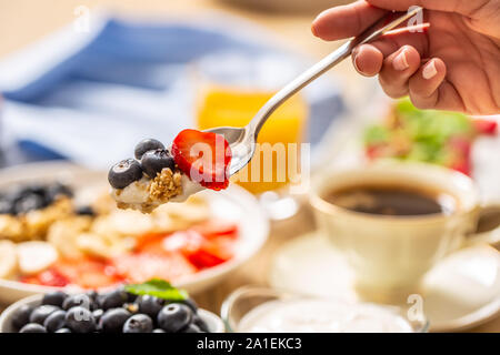 Gesundes Frühstück auf Löffel Müsli Heidelbeere Joghurt und Erdbeeren auf Gabel Stockfoto