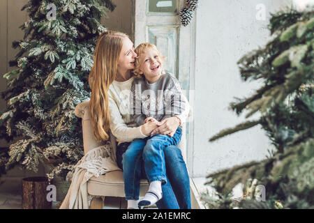 Portrait der glücklichen Mutter und bezaubernde junge Weihnachten feiern. Das neue Jahr Urlaub. Kleinkind bei Mama in der festlich dekorierten Zimmer mit Weihnachten tr Stockfoto