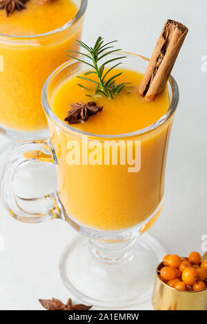 Schließen Sie zwei Tassen mit heißem hippophae Tee mit Kräutern und Zimt auf hellen Hintergrund. Konzept der saisonale Getränke. Sanddorn gesundes Getränk Stockfoto