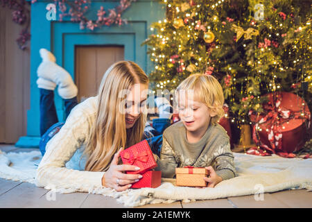 Portrait der glücklichen Mutter und bezaubernde junge Weihnachten feiern. Das neue Jahr Urlaub. Kleinkind bei Mama in der festlich dekorierten Zimmer mit Weihnachten tr Stockfoto