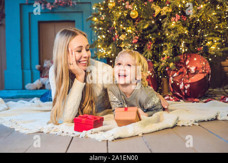 Portrait der glücklichen Mutter und bezaubernde junge Weihnachten feiern. Das neue Jahr Urlaub. Kleinkind bei Mama in der festlich dekorierten Zimmer mit Weihnachten tr Stockfoto