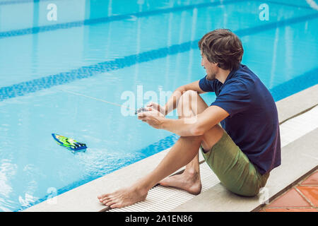 Mann spielt mit einem ferngesteuerten Boot im Pool. Stockfoto