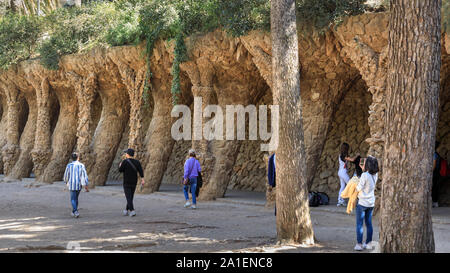 Menschen gehen durch die Kolonnaden des organischen Steinsäulen in Park Guell, von Antonio Gaudí in Barcelona, Spanien, Stockfoto