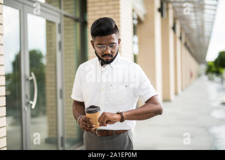 Schöne indische Hipster genießen Sie eine Fahrt mit dem Fahrrad und Überprüfung auf seine Armbanduhr. Stockfoto